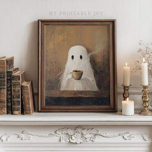 Peut inclure: Une œuvre encadrée représente un fantôme blanc tenant une tasse de café, de la vapeur s'échappant. L'œuvre est dans un cadre en bois brun foncé. Le texte "MY PRINTABLE JOY" est en haut. L'œuvre est exposée sur une cheminée blanche avec des bougies et des livres.