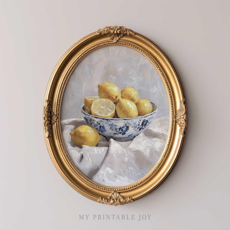 May include: A painting of lemons in a blue and white bowl, set on a white tablecloth. The painting is framed in a gold ornate frame.