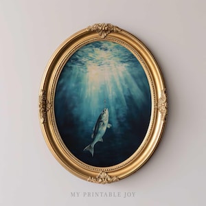 May include: A gold oval frame with a painting of a fish swimming in the ocean. The fish is facing the viewer and is in the center of the painting. The ocean is a deep blue color and there are sunbeams shining down from the surface.
