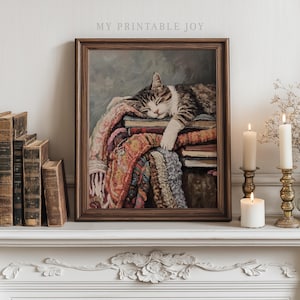 May include: A framed print of a sleeping cat resting on a stack of books and a colorful blanket. The artwork has a vintage aesthetic, with the text "MY PRINTABLE JOY" at the top. The scene is lit by candles.