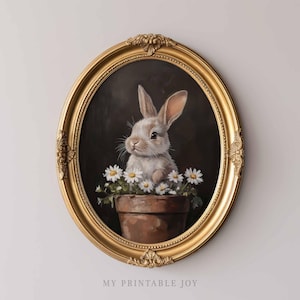 May include: A framed painting of a white rabbit sitting in a pot of white daisies. The rabbit has brown eyes and a pink nose. The painting is in a gold oval frame.