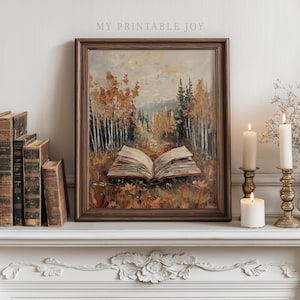 May include: A framed landscape painting depicts an open book in a forest scene with autumn colors. The artwork features a brown wooden frame, with the text "MY PRINTABLE JOY" at the top. Candles in brass holders and antique books are also visible.