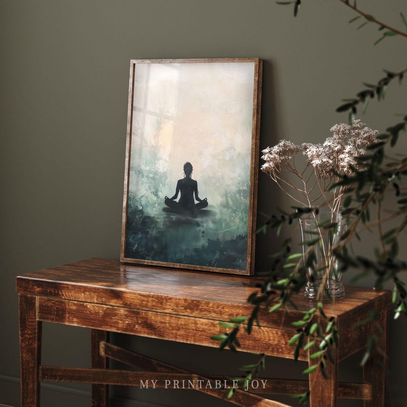May include: A framed print of a silhouette of a person sitting in a yoga pose against a background of blue and green watercolor washes.