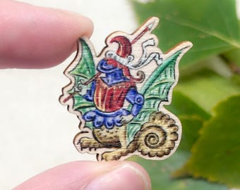 May include: A wooden cutout of a fantastical creature with green wings, a red and blue suit of armor, and a spiral tail. The creature is holding a spear and wearing a red hat.