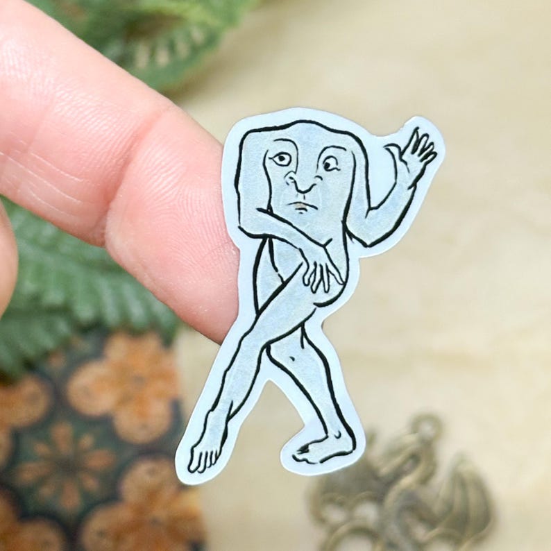 May include: A light blue sticker featuring a stylized illustration of a humanoid figure with a square head, arms, and legs. The figure is depicted in a walking pose, with one arm raised and the other crossed over its body. The sticker has a white border.