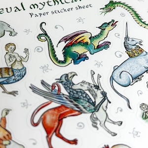 May include: A paper sticker sheet featuring medieval mythical creatures. The stickers include a green dragon with red and yellow wings, a unicorn wearing a gold crown, and a griffin. The text "Paper sticker sheet" is visible.