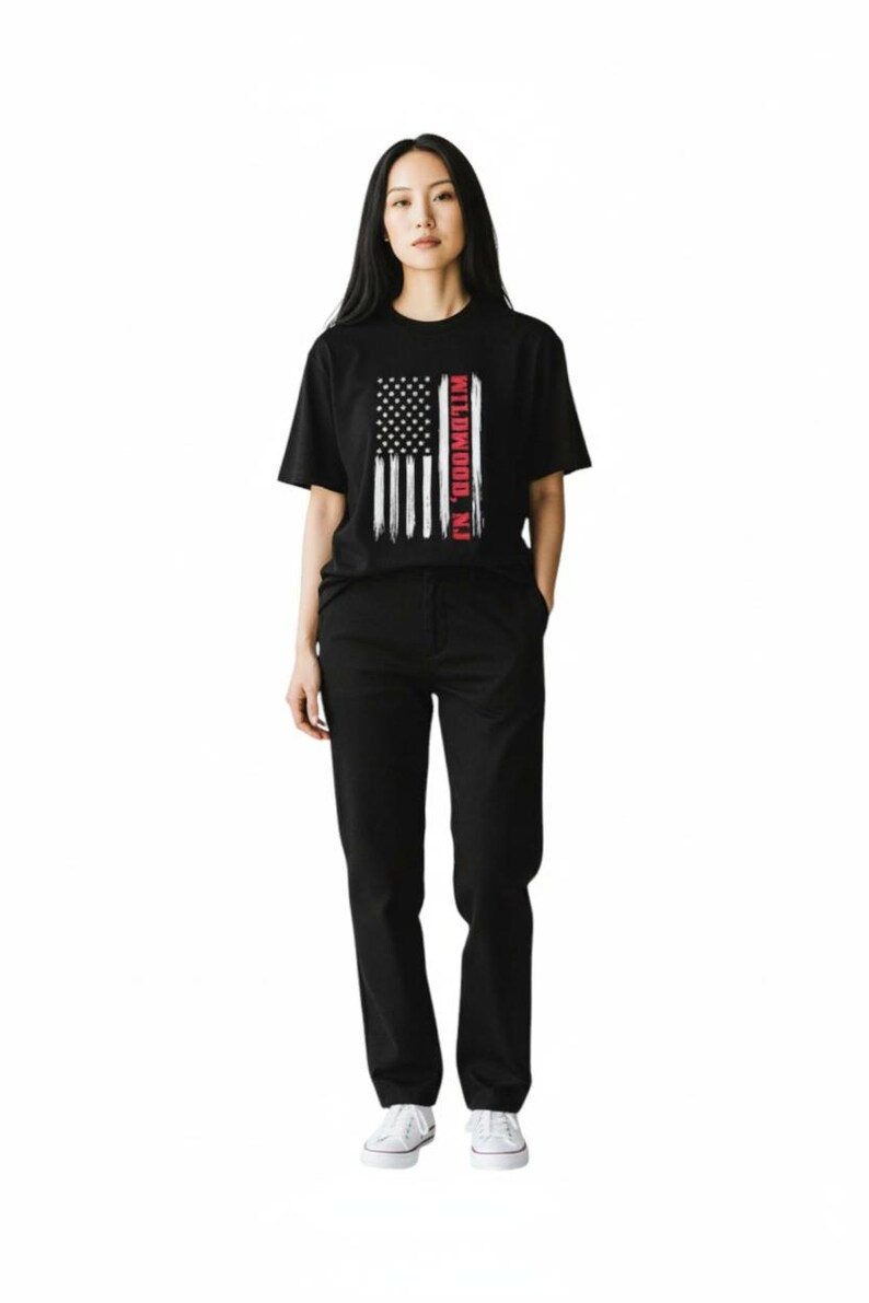 May include: A person wearing a black t-shirt with an American flag design and the text "Wildwood, NJ". The person is also wearing black pants and white sneakers. The outfit is casual and simple.