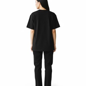 May include: A person wearing a black t-shirt and black pants. The t-shirt has short sleeves and a crew neck. The pants are straight-legged. The person is wearing white sneakers with a black stripe.