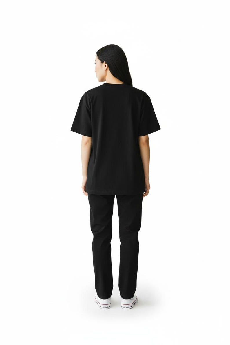 May include: A person wearing a black t-shirt and black pants. The t-shirt has short sleeves and a crew neck. The pants are straight-legged. The person is wearing white sneakers with a black stripe.
