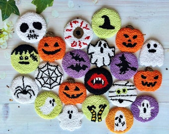 May include: A collection of 18 Halloween-themed felt ornaments. The ornaments are round and feature various designs, including a ghost, a spider, a pumpkin, a witch's hat, and a skull. The ornaments are all white with black details.