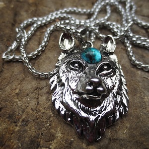 May include: A silver wolf head pendant necklace with a blue gemstone eye. The chain is silver and has a curb link style.