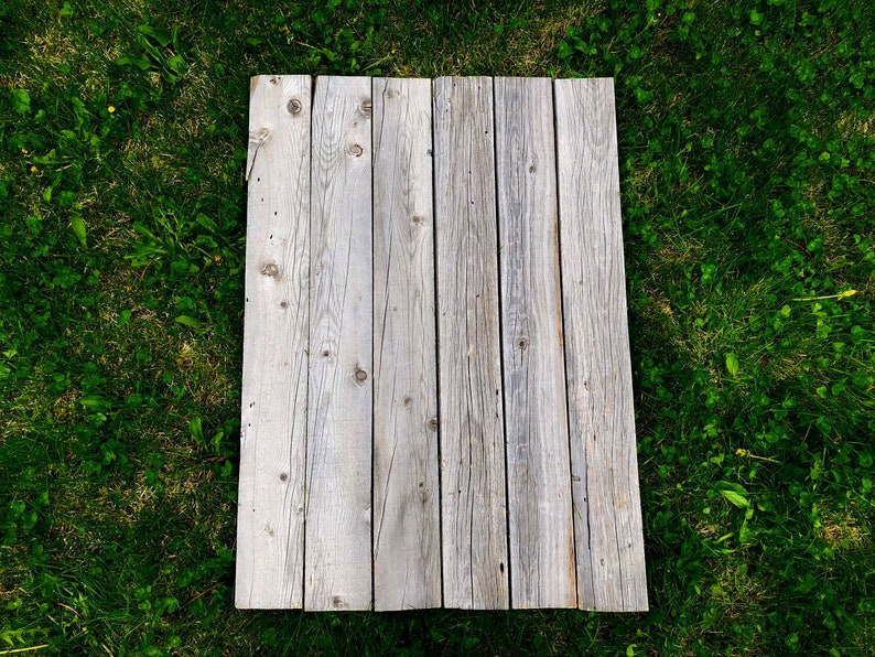 May include: A weathered wooden plank surface with a light gray color. The planks are arranged horizontally and have a rustic appearance.