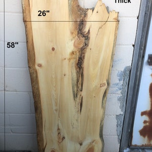 May include: A large, natural wood slab with a live edge. The slab is 58 inches long, 26 inches wide, and 1 1/2 inches thick. The wood has a light brown color with dark brown knots and grain patterns. The slab is labeled "LP1".