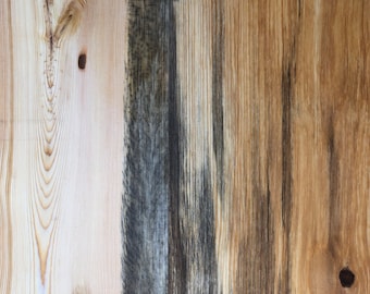 May include: Close-up of a wooden surface with three vertical planks. The planks are different colors, with one being a light wood, one being a dark wood, and one being a medium brown wood. The wood has a natural grain pattern.