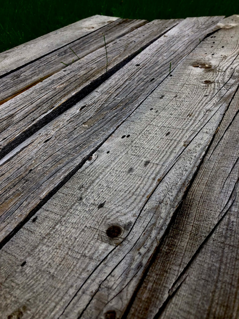 May include: Close-up of weathered wooden planks, showing the natural grain and texture of the wood. The planks are arranged in a diagonal pattern, creating a rustic and aged look.