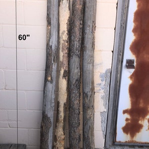 May include: Set of four rough-hewn wooden posts, each approximately 60 inches long. The posts are weathered and have a natural, rustic look.  Set 1.