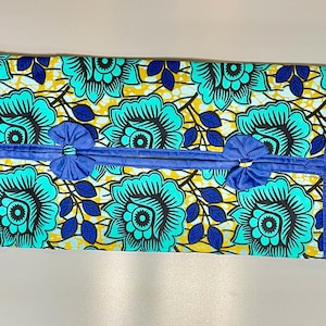 May include: A blue and yellow fabric tissue box cover with a floral pattern and blue ribbon accents.