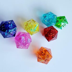 May include: Set of six iridescent dice in various colors, including blue, yellow, pink, red, green, and orange. Each die has black numbers.