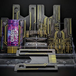 May include: A clear plastic card holder with multiple black and yellow circuit board-style dividers. A card with the word "CHAOS" in purple and white is visible. The text "UNPREDICTABLE BEWARE" and "DRAW REARRANGE COVERED" are also visible.