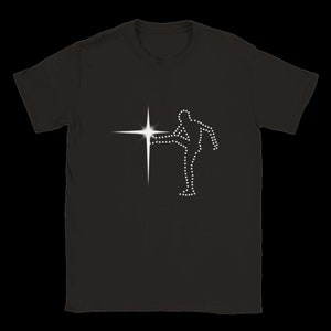 Può includere: T-shirt nero con grafica bianca di una persona che calcia una stella. Il disegno è composto da piccoli punti bianchi, creando una silhouette. La stella è di colore bianco brillante.