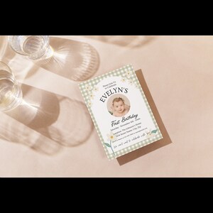 Puede incluir: Una invitaci&oacute;n con estampado de vichy verde y blanco con una foto de una ni&ntilde;a peque&ntilde;a. La invitaci&oacute;n dice "Por favor, &uacute;nase a nosotros para celebrar el primer cumplea&ntilde;os de EVELYN" e incluye la fecha, la hora, el lugar y la informaci&oacute;n de RSVP.