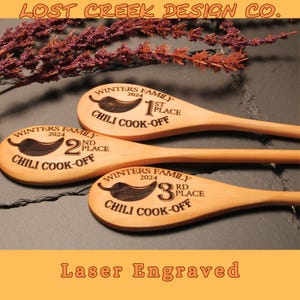 May include: Three wooden spoons with laser engraved chili pepper designs and text. The spoons are labeled "Winters Family 2024" and indicate 1st, 2nd, and 3rd place in a chili cook-off.