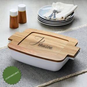 Puede incluir: Una fuente rectangular blanca con tapa de madera grabada con el nombre "Johnson". Se ven dos saleros y pimenteros de madera con tapas blancas. La palabra "PERSONALIZABLE" está en una pegatina verde.