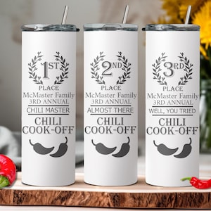 May include: Three white stainless steel tumblers with black text and chili pepper graphics. The tumblers are labeled "1st Place McMaster Family 3rd Annual Chili Master Chili Cook-Off", "2nd Place McMaster Family 3rd Annual Almost There Chili Cook-Off", and "3rd Place McMaster Family 3rd Annual Well, You Tried Chili Cook-Off".