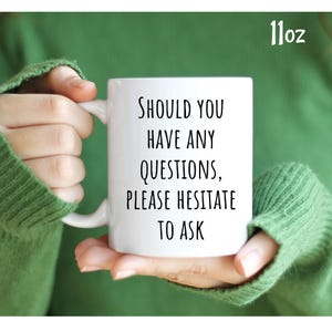 May include: White ceramic mug with black text that reads "Should you have any questions, please hesitate to ask".