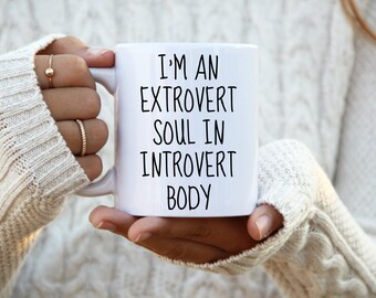 May include: White ceramic mug with black text that reads "I'm an extrovert soul in introvert body".