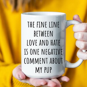 May include: White ceramic mug with black text that reads "The fine line between love and hate is one negative comment about my pup."