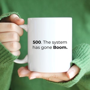 May include: White ceramic mug with black text that reads "500. The system has gone Boom."