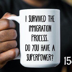 May include: White ceramic coffee mug with black text that reads "I survived the immigration process. Do you have a superpower?" and "15oz".