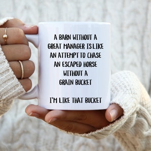May include: White ceramic mug with black text that reads: "A barn without a great manager is like an attempt to chase an escaped horse without a grain bucket. I'm like that bucket."