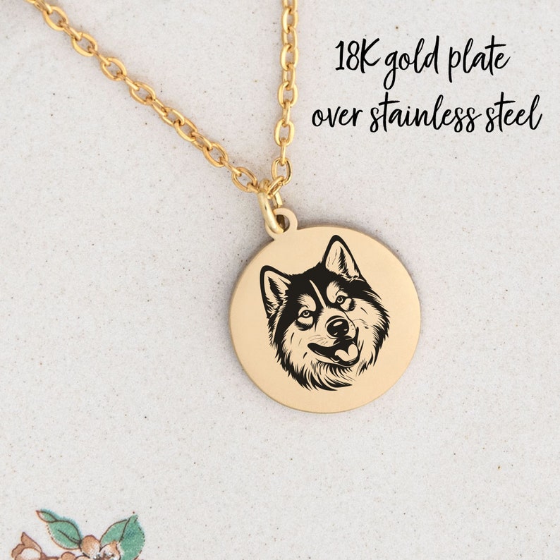 May include: Gold necklace with a round pendant featuring a black and white husky dog silhouette. The necklace is made of stainless steel with 18K gold plating. "18K gold plate over stainless steel" is written in white text on a white background.