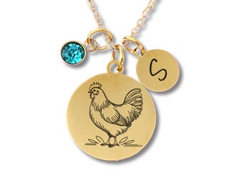 May include: Gold necklace with a charm featuring a line drawing of a chicken, a small blue crystal charm, and a gold charm with the letter 'S'.