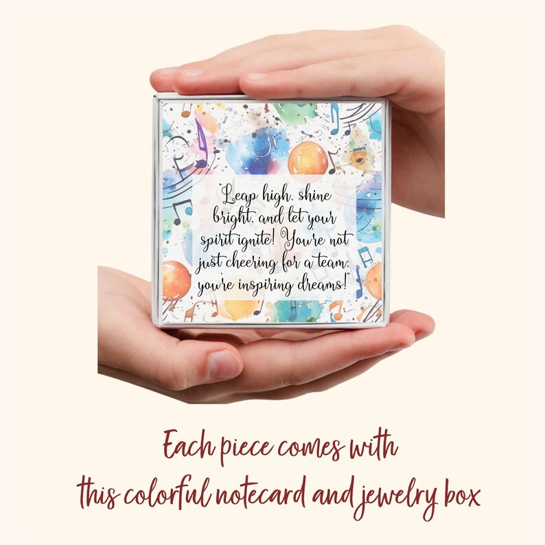 Puede incluir: Una caja de joyer&iacute;a colorida con una cita motivacional: "Leap high, shine bright, and let your spirit ignite! You're not just cheering for a team; you're inspiring dreams!" La caja est&aacute; decorada con notas musicales y salpicaduras de acuarela.