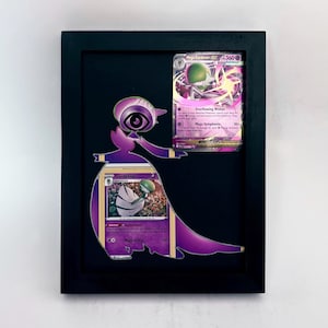 Könnte beinhalten: Ein gerahmtes Kunstwerk mit zwei Pokémon-Sammelkarten und einem lila Gardevoir-Ausschnitt. Die Karten werden vor einem schwarzen Hintergrund in einem schwarzen Rahmen präsentiert. Der Gardevoir-Ausschnitt ist so positioniert, dass er mit den Karten interagiert.