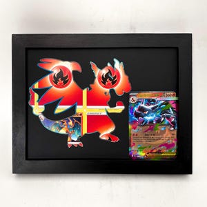 Puede incluir: Un marco rectangular negro tipo caja que contiene una gran silueta recortada con forma de dragón, superpuesta con símbolos de energía de fuego rojos y naranjas y una ilustración de Charizard, junto a una carta coleccionable.