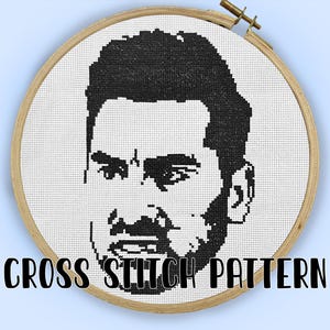 May include: A cross-stitch pattern showing a black and white portrait of a person's face, set within a round wooden embroidery hoop. The words "CROSS STITCH PATTERN" are printed in black below the image.
