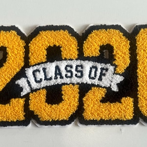 May include: A yellow and black embroidered patch with the text "2026 CLASS OF" in a banner. The numbers are yellow with black outlines, and the banner is white with black text. The patch is likely for graduation.