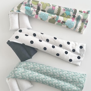 May include: Three rectangular heating pads with different fabric patterns. One has a cactus print, another has large black polka dots on white, and the third has a small floral pattern in shades of green. Each pad has a white end piece.