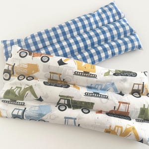 May include: Two rectangular heating pads. One is white with a pattern of construction vehicles in various colors. The other is blue and white checkered. Both pads are quilted with horizontal stitching.