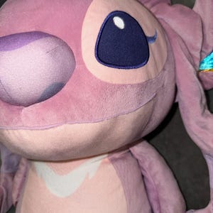 Puede incluir: Un peluche rosa de un personaje con grandes ojos azules y largas orejas. El juguete tiene una textura suave y difusa y una expresi&oacute;n amigable. El dise&ntilde;o incluye un parche blanco en el pecho.