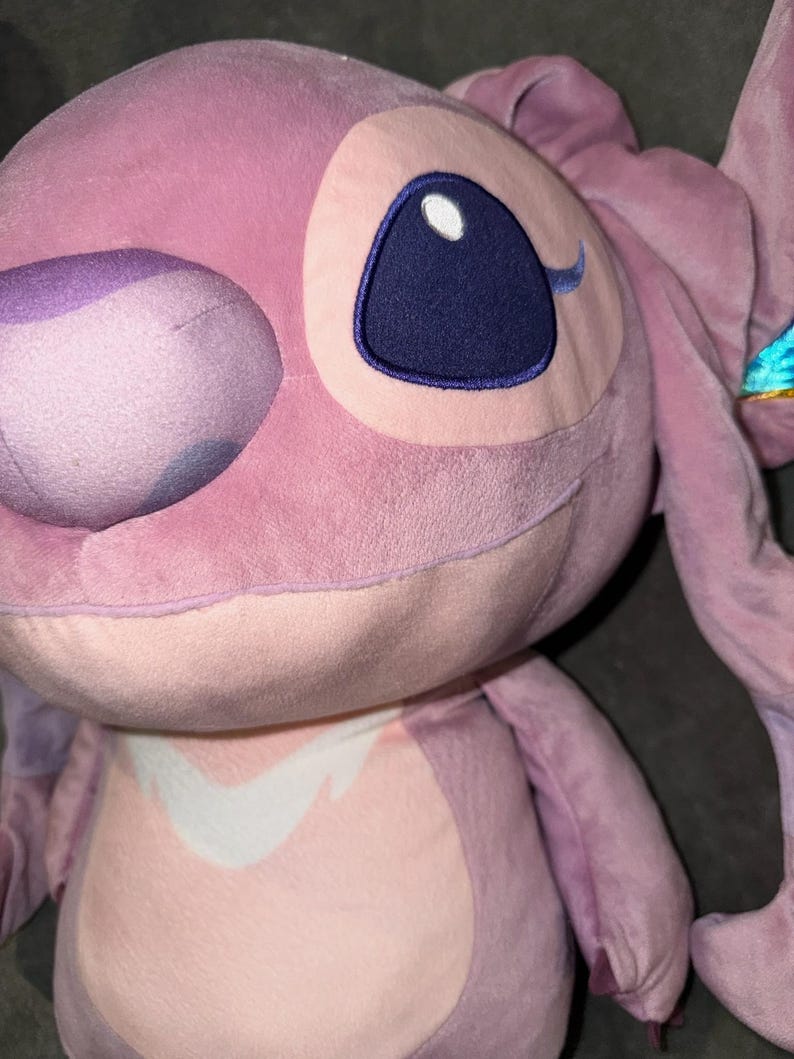 Puede incluir: Un peluche rosa de un personaje con grandes ojos azules y largas orejas. El juguete tiene una textura suave y difusa y una expresi&oacute;n amigable. El dise&ntilde;o incluye un parche blanco en el pecho.