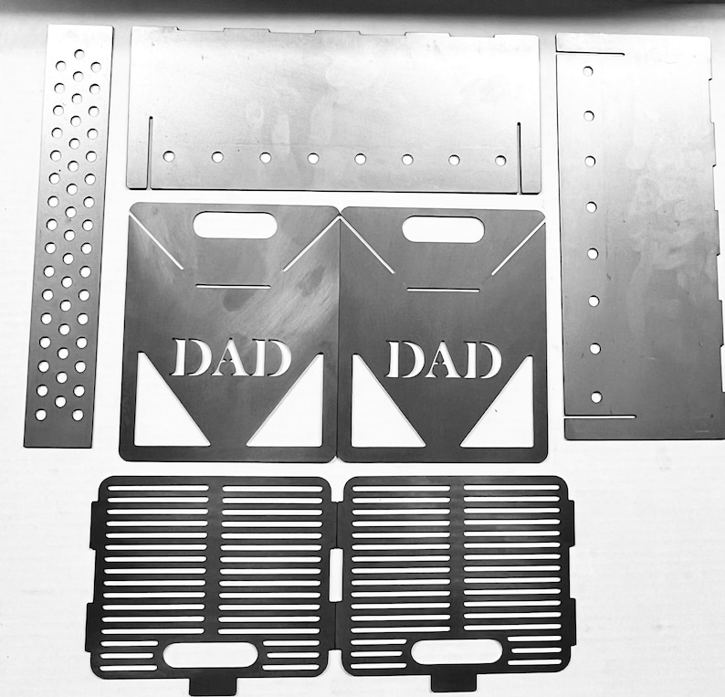 May include: A set of metal fire pit parts, including two side panels with the word "DAD" cut out, a grate, and two side panels with holes.