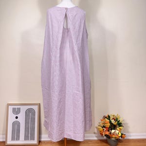 May include: A sleeveless, lilac-colored dress with a small red and white grid pattern. The dress has a keyhole back and a button closure at the neckline. The dress is displayed on a mannequin.