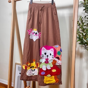 Pantalones anchos con apliques de gato hechos a mano: lino y algodón marrón con patchwork de dibujos animados. Prendas artísticas divertidas para artistas y educadores.