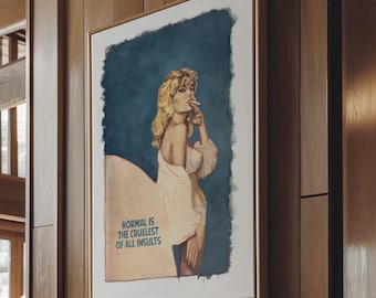May include: A framed vintage-style print with a blonde woman in a white robe, set against a blue background. The print is in a gold frame and hangs on a wood-paneled wall. The text on the print reads "NORMAL IS THE CRUELEST OF ALL INSULTS."