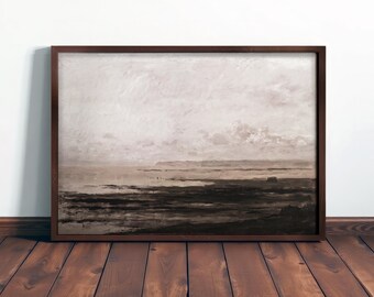 May include: A framed landscape painting in muted tones of brown, beige, and gray. The artwork depicts a coastal scene with a cloudy sky, a body of water, and a dark foreground. The frame is a dark brown color.